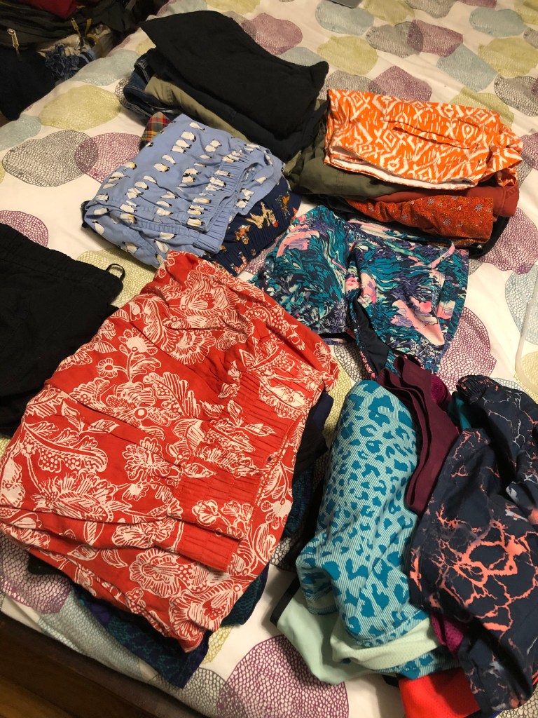 folded skirts and shorts on a bed.